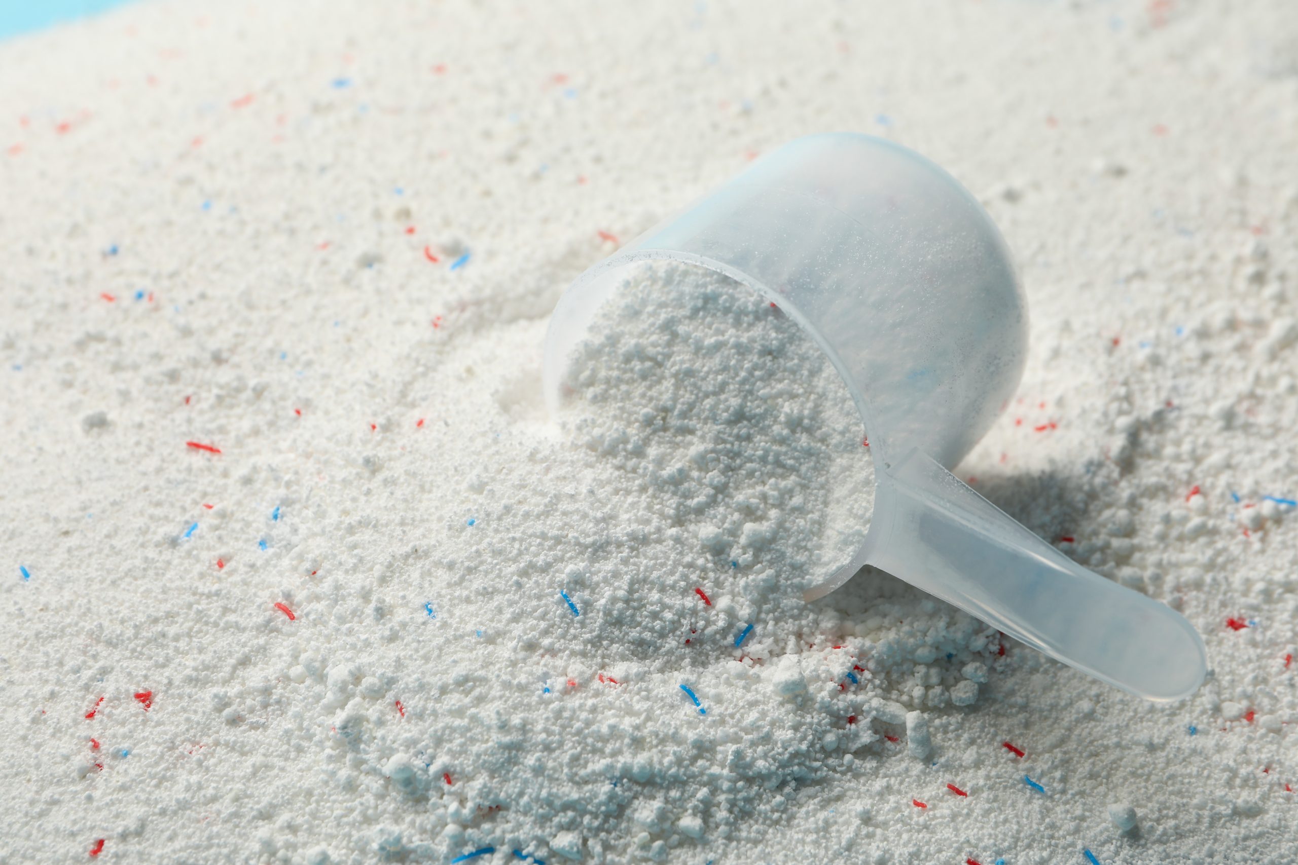 Scoop with washing powder on washing powder background